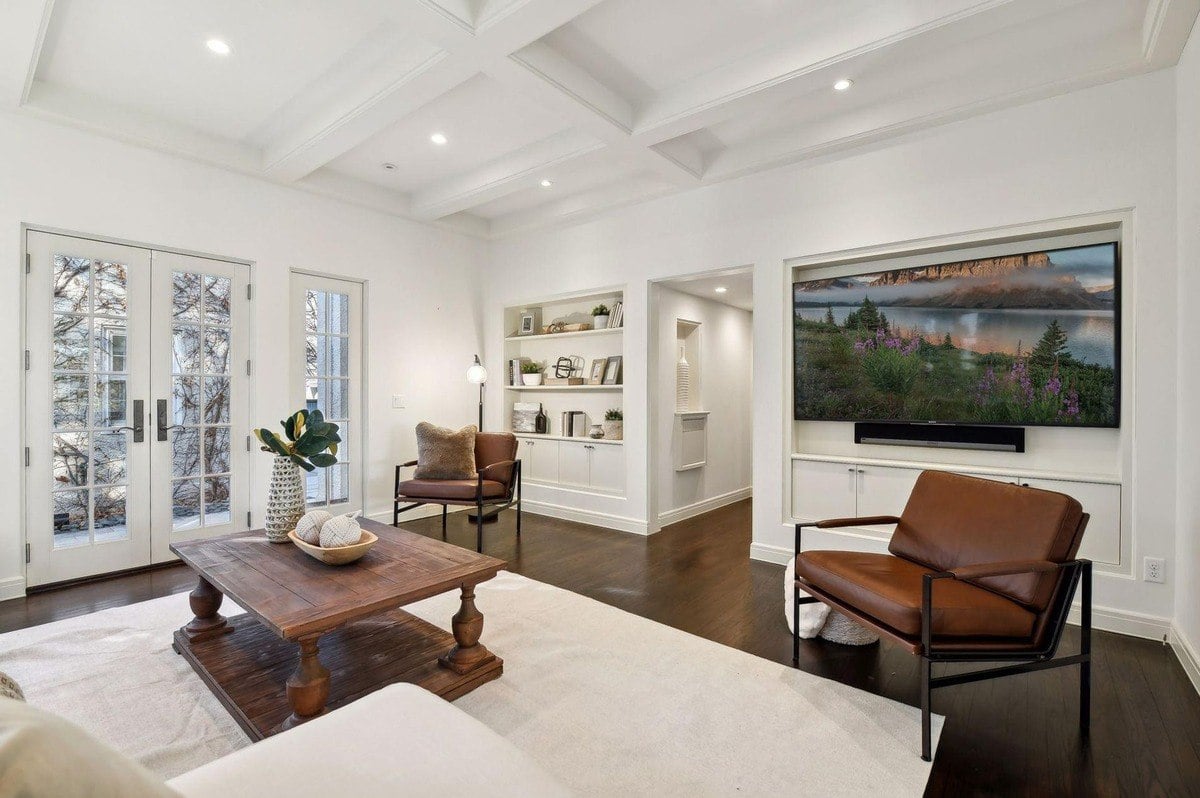 Family room with built-in shelving, French doors, and a large flat-screen TV.