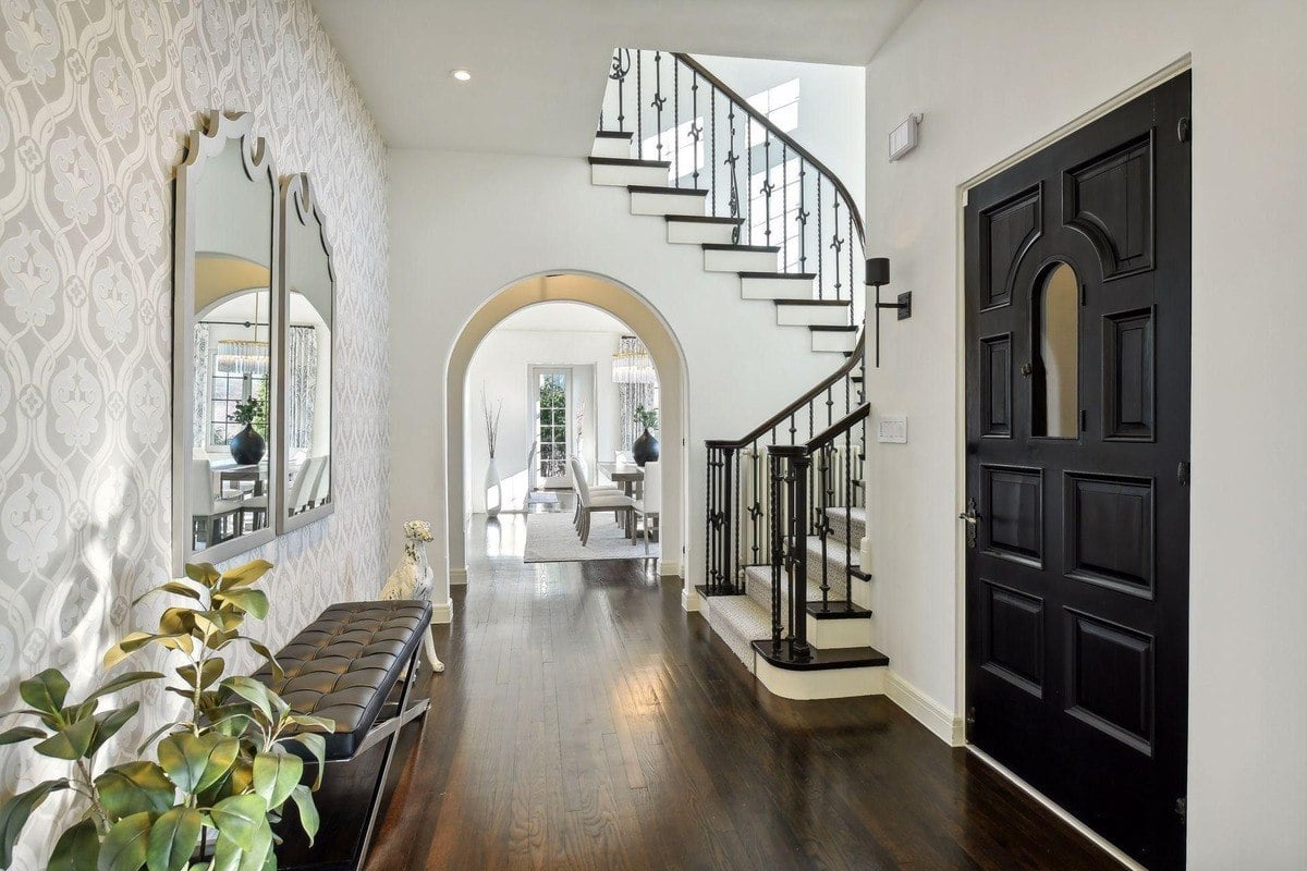 Entryway with a curved staircase, dark hardwood floors, and a view into a dining room.