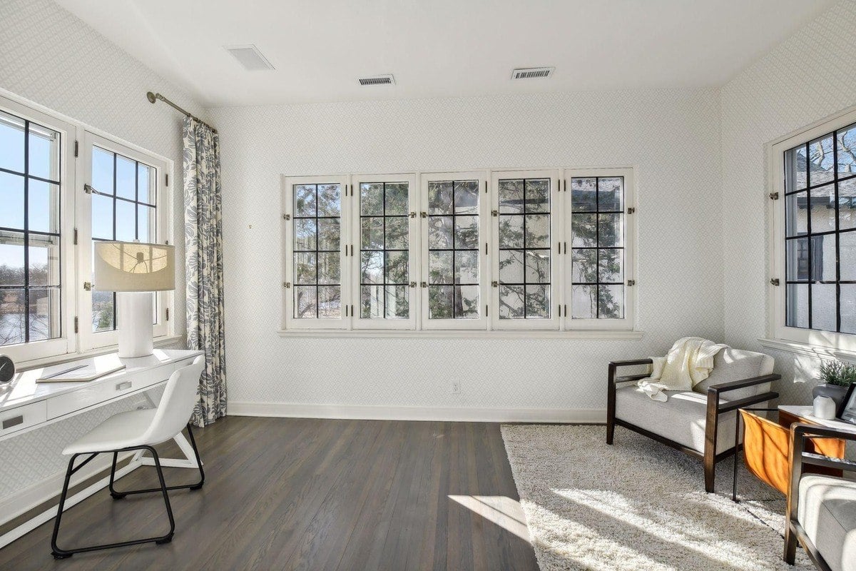 Room with hardwood floors, white walls, and large windows.