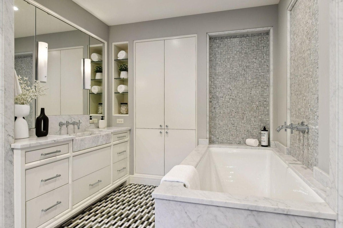 Bathroom with marble countertops, a soaking tub, and gray walls.