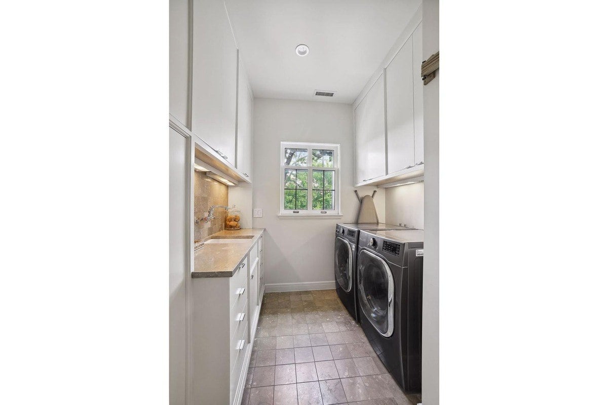 Laundry room with white cabinets, a sink, and a washer and dryer.