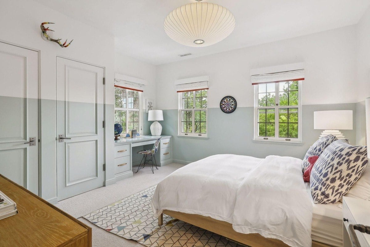 Bedroom with a bed, desk, and light blue and white walls.