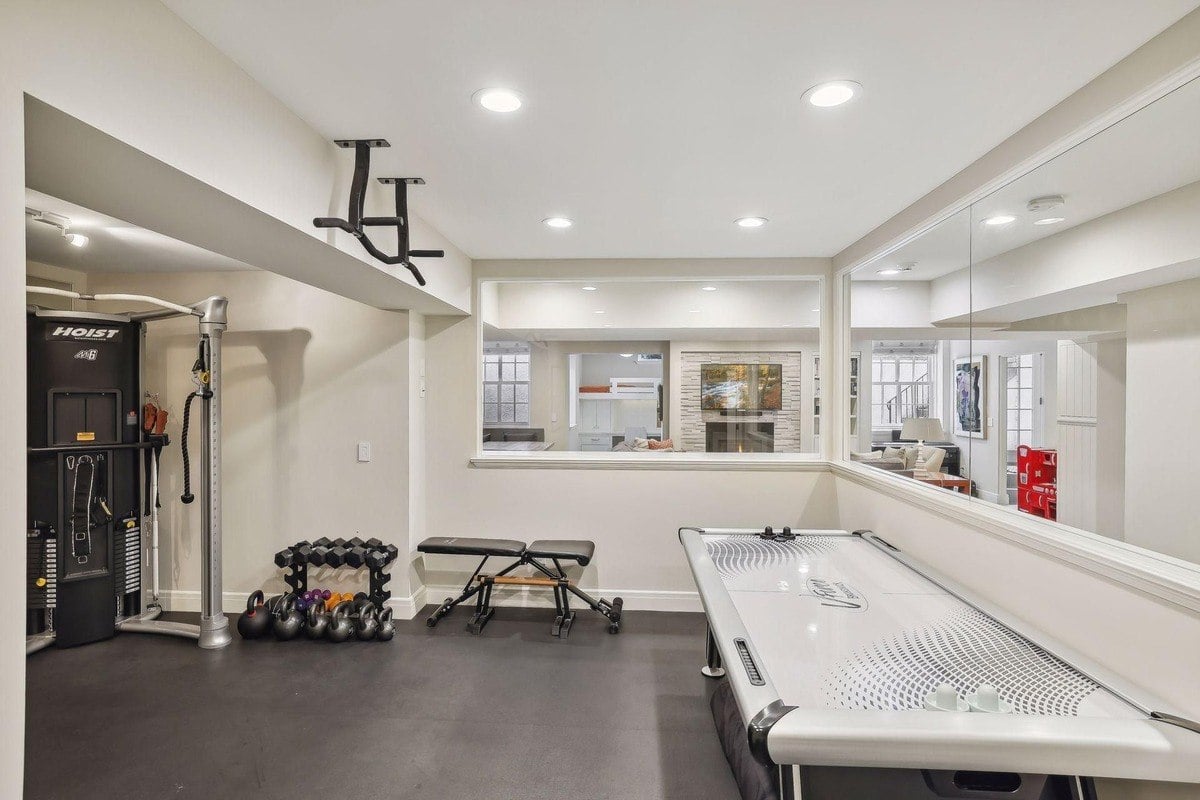 Basement game room with exercise equipment, air hockey table, and a view into another room.