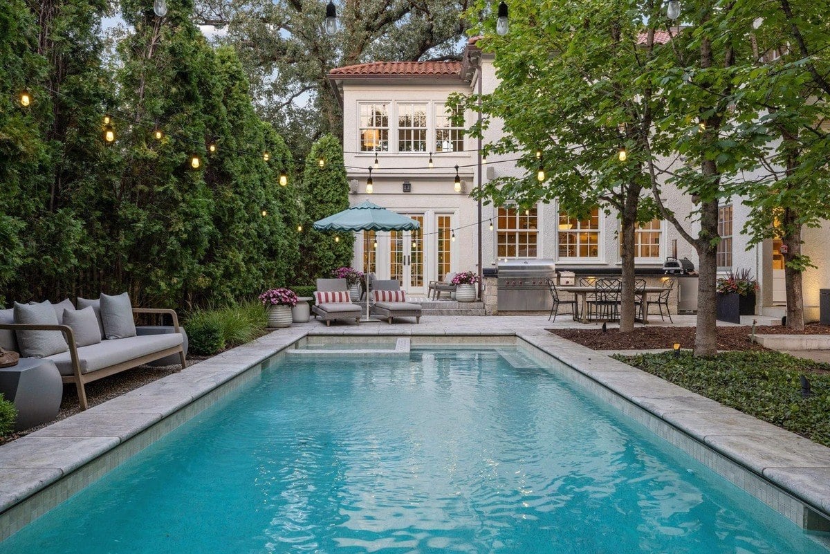 Backyard with a swimming pool, lounge chairs, and string lights.