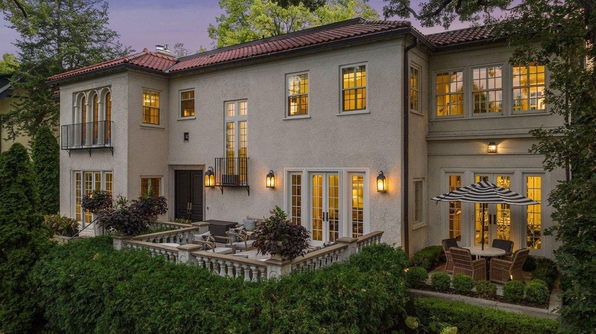 Back of a large house with a patio, and outdoor seating area.