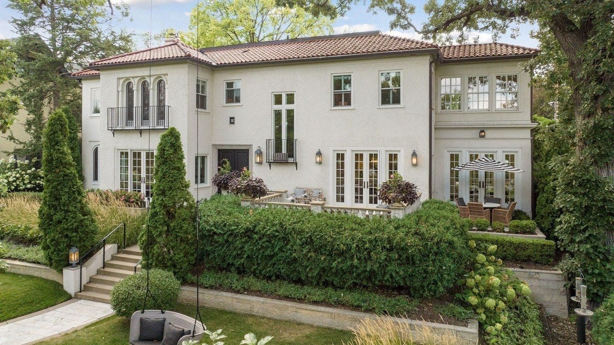 Large white house with a red tile roof, surrounded by landscaping and a patio.