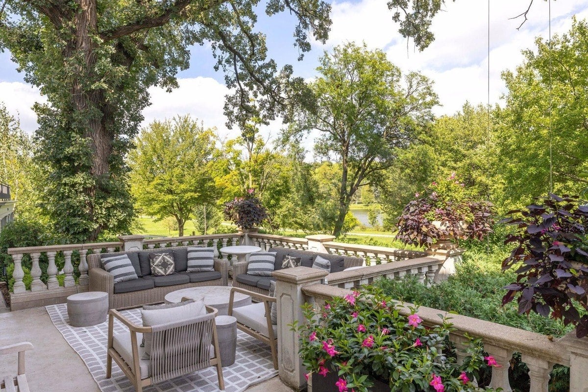 Outdoor patio furniture with a view of lush green trees and a lake.