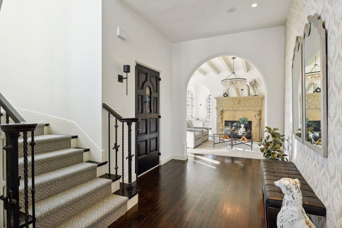 Entryway with staircase, dark wood floors, and view into living room with fireplace.
