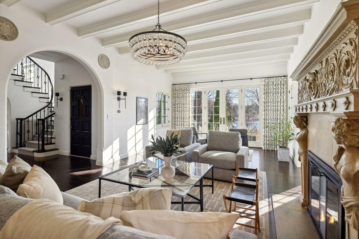 Living room with large windows, fireplace, and a view of a staircase.