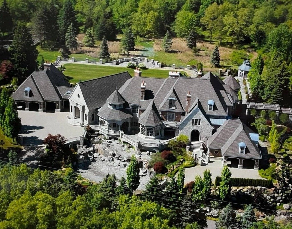 Aerial view showcases an expansive estate with intricate architecture surrounded by lush greenery.