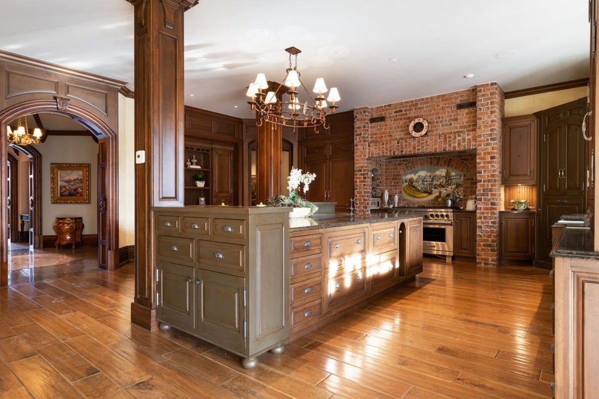 Brick-accented kitchen with a central island and modern appliances integrated into classic design elements.