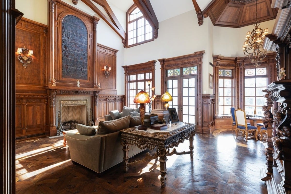 Grand living room showcases intricate wood paneling, a cathedral ceiling, and stained-glass details.