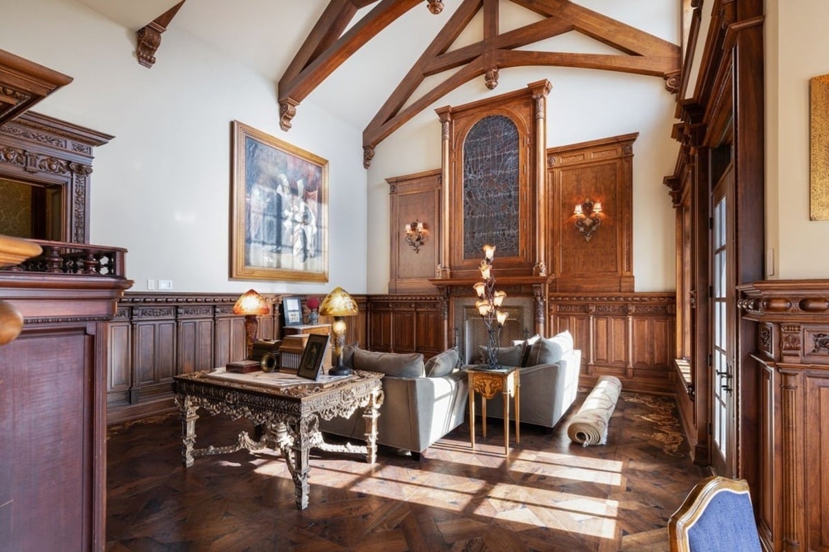 Sitting area highlights vaulted ceilings, custom millwork, and a decorative fireplace.