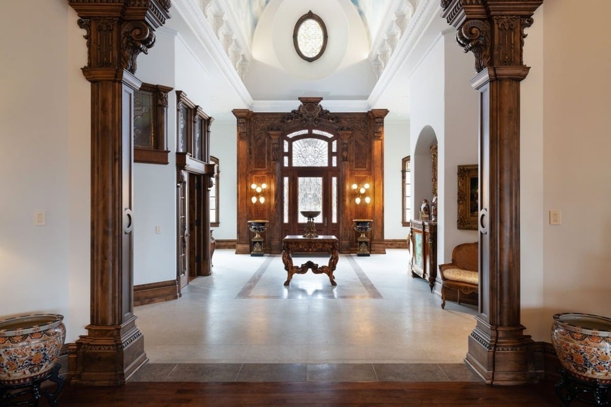 Entrance hall with ornate woodwork and a vaulted ceiling featuring a central skylight and detailed decor.