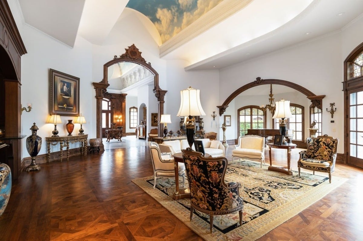 formal dining room with a central chandelier, ornate wood details, and large windows offering natural light.