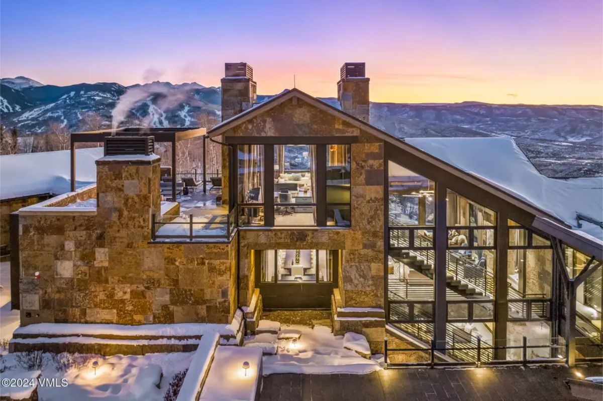 Situated in a scenic alpine setting, this contemporary home combines stone and glass architecture with breathtaking views of surrounding ski slopes and mountains.