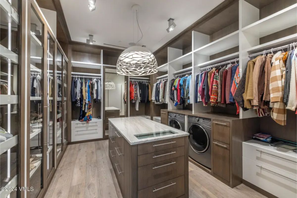 Walk-in closet is organized with custom cabinetry and glass-fronted storage for clothing and accessories.