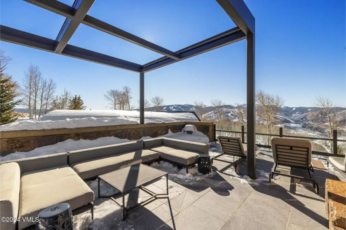 An elevated outdoor lounge provides panoramic views of snow-capped mountains and pristine forests.