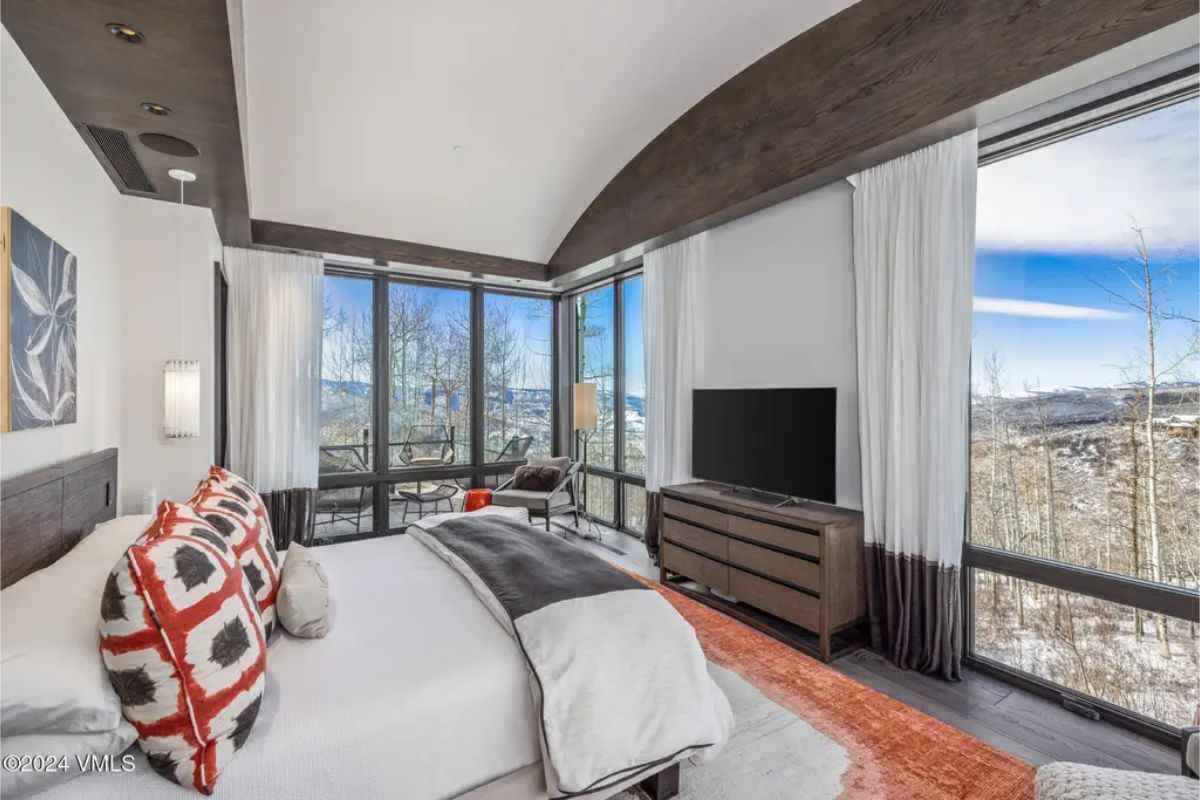 A bright and airy bedroom featuring floor-to-ceiling windows that offer stunning mountain vistas.