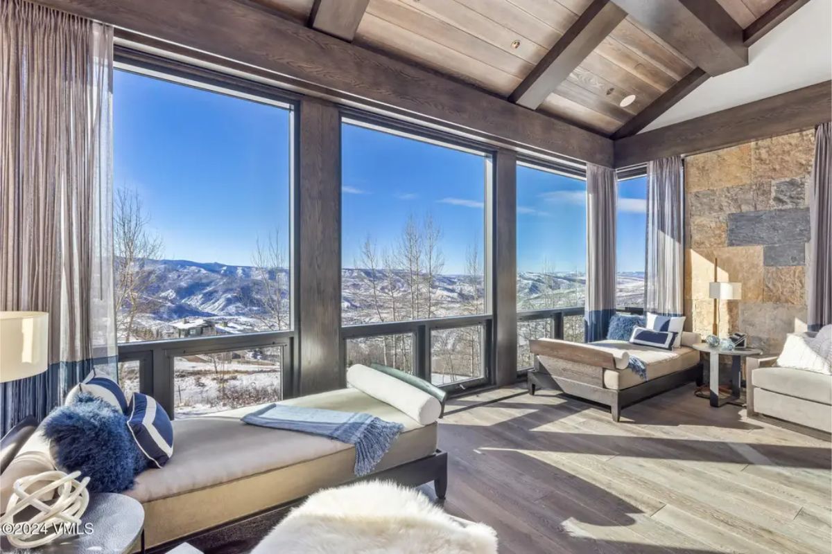 Lounge area is framed by floor-to-ceiling windows that offer panoramic views of the snow-covered mountains.