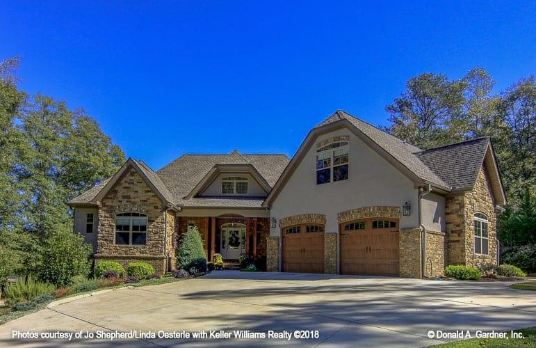 Classic Stone Facade with Double Garage Doors in a Picturesque Setting