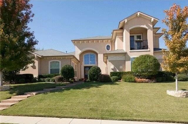 Elegant Two-Story Home with Arched Windows and Manicured Lawn
