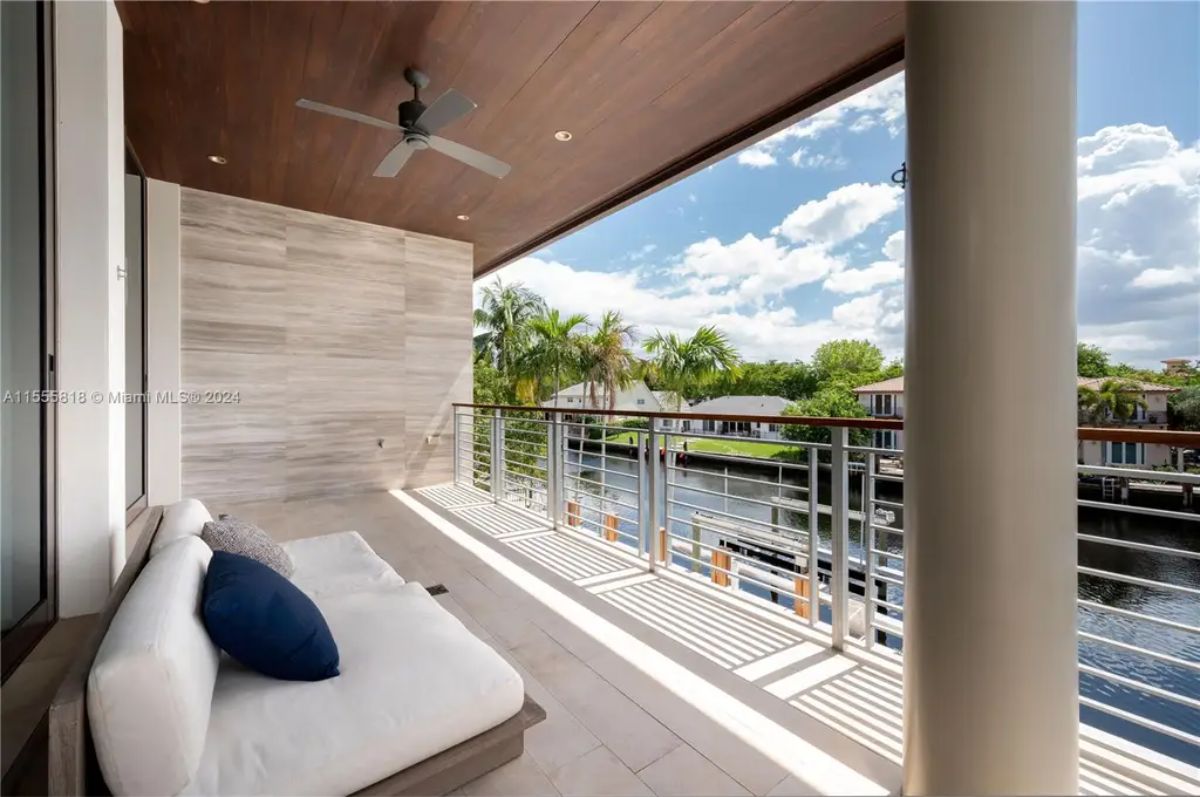A private balcony with a wooden ceiling, plush seating, and a view of the tranquil waterway provides a relaxing retreat. 