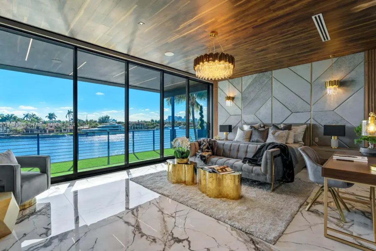 Floor-to-ceiling glass doors open to a balcony overlooking the water and yachts.
