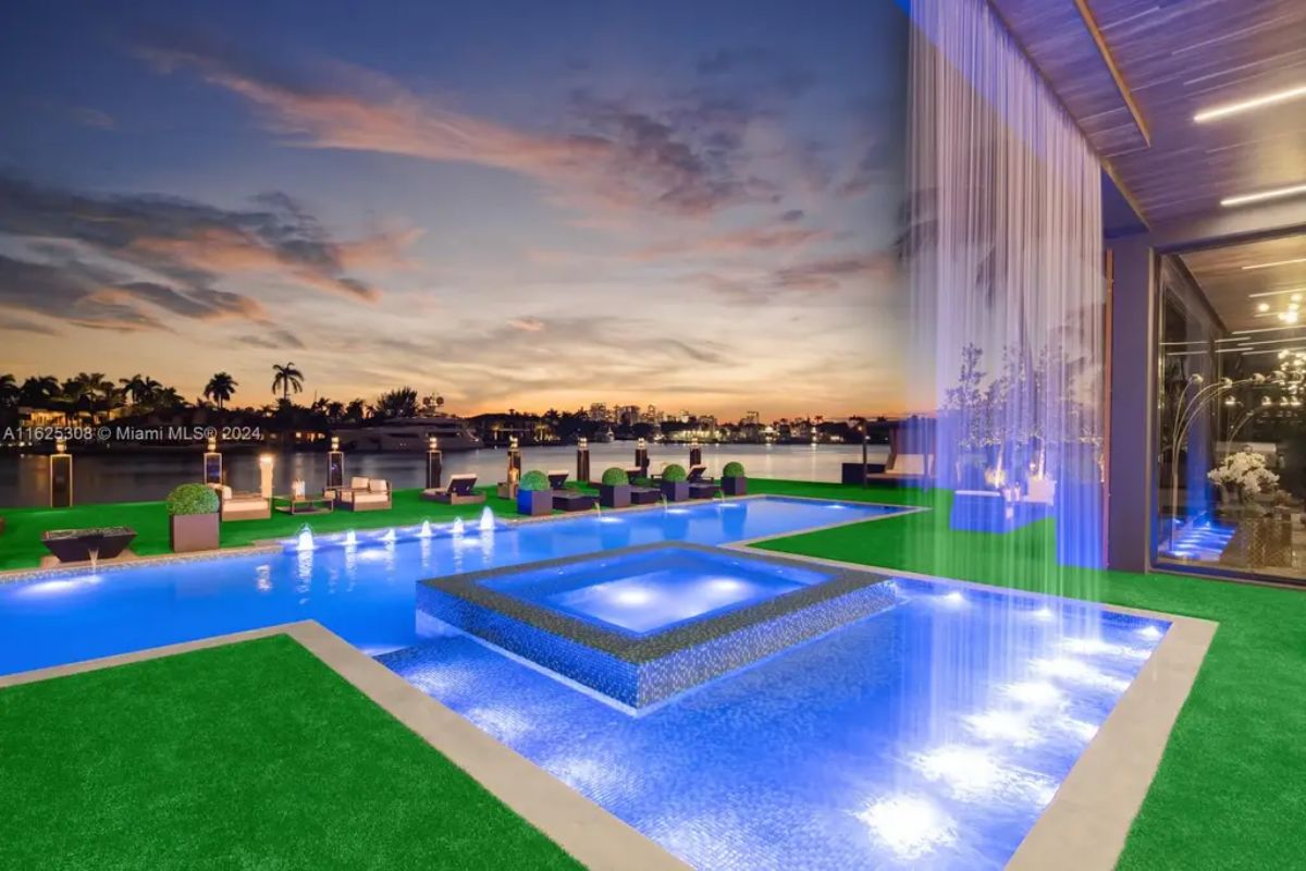 Multi-level pool with LED lighting and a built-in spa overlooks the waterfront at sunset.