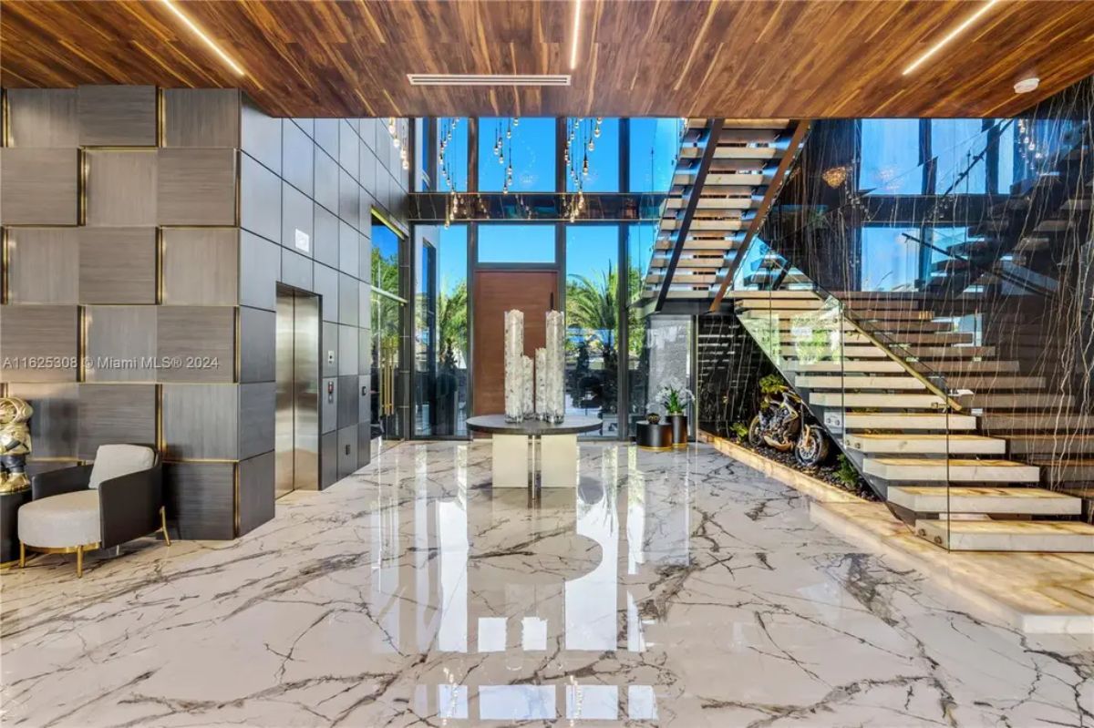 High-ceiling entryway features marble flooring, wood-paneled ceilings, and floor-to-ceiling glass walls.