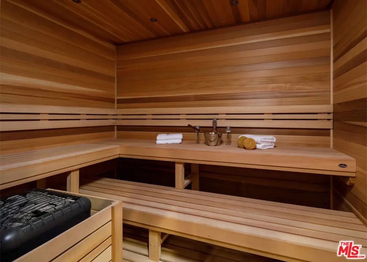Wooden sauna room with tiered seating, neatly folded towels, and traditional sauna accessories. 