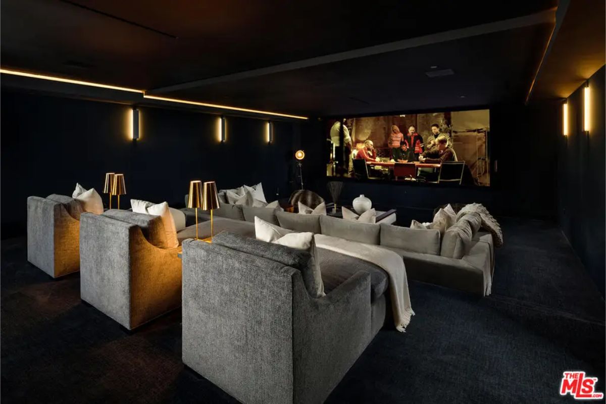 Home theater with cozy gray seating and soft ambient lighting, featuring a large screen showing a movie scene. 