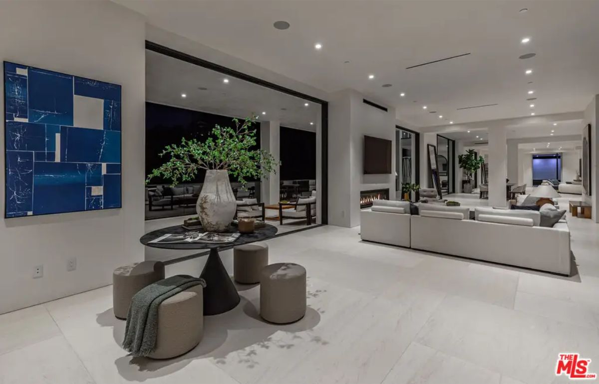 Open-plan living space blends indoor and outdoor areas seamlessly, with cozy seating, minimalist décor, and striking modern art. 