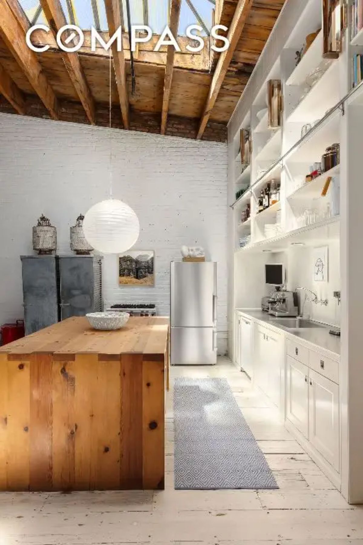 White cabinetry and open shelving contrast with a wooden island.