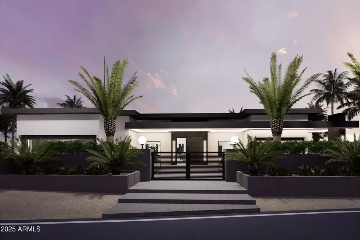 Symmetrical palm trees and lush greenery frame a black metal entry gate.