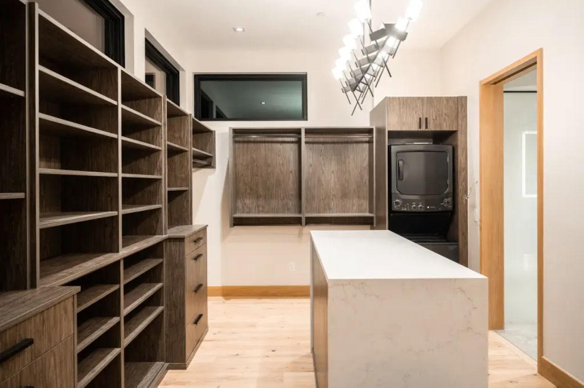 Walk-in closet with dark wood shelving, an island countertop, and a laundry station. 