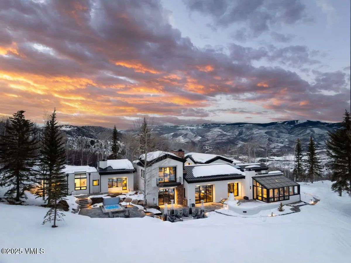 Modern home set against snow-covered mountains with large windows maximizing natural light.