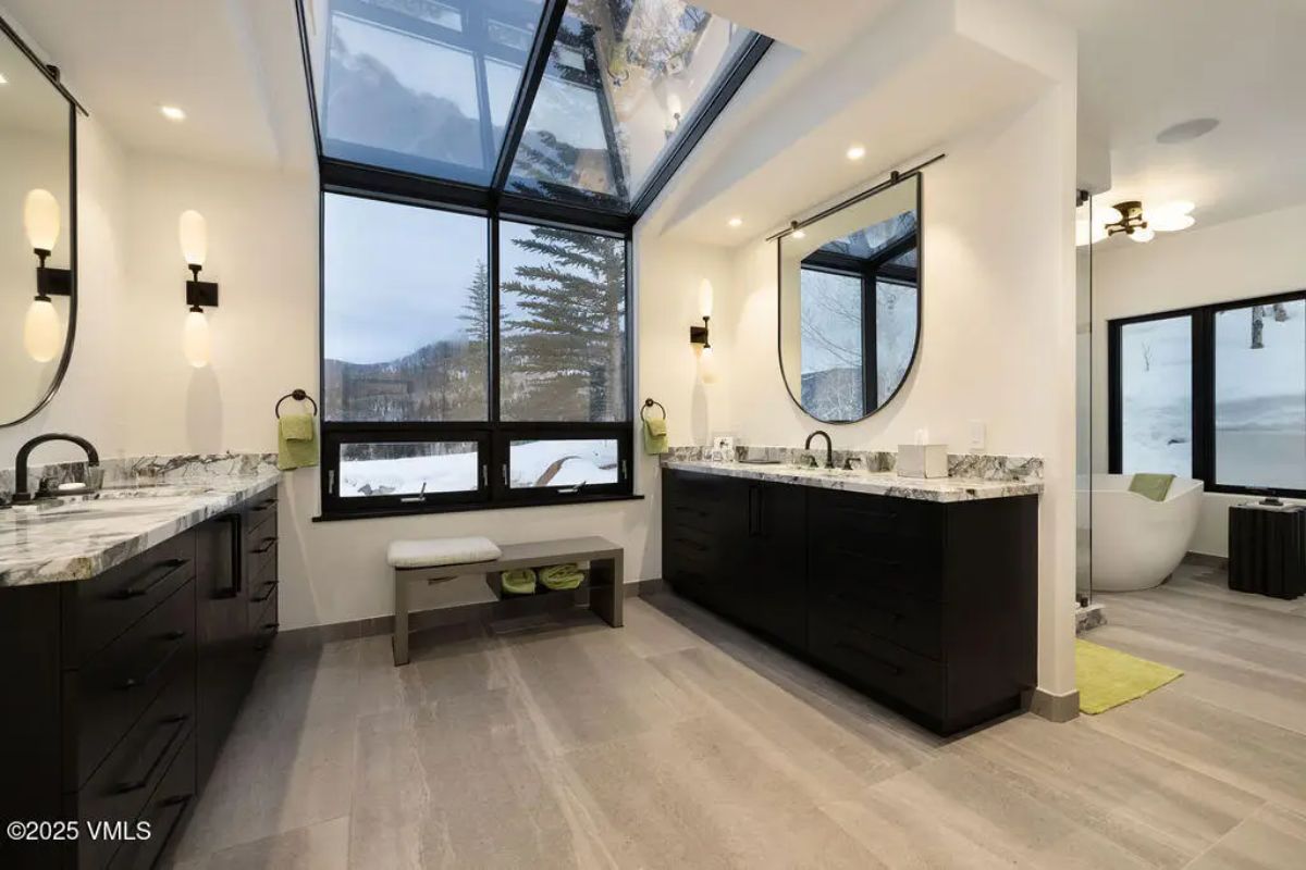 Dual dark wood vanities topped with white and gray marble countertops.