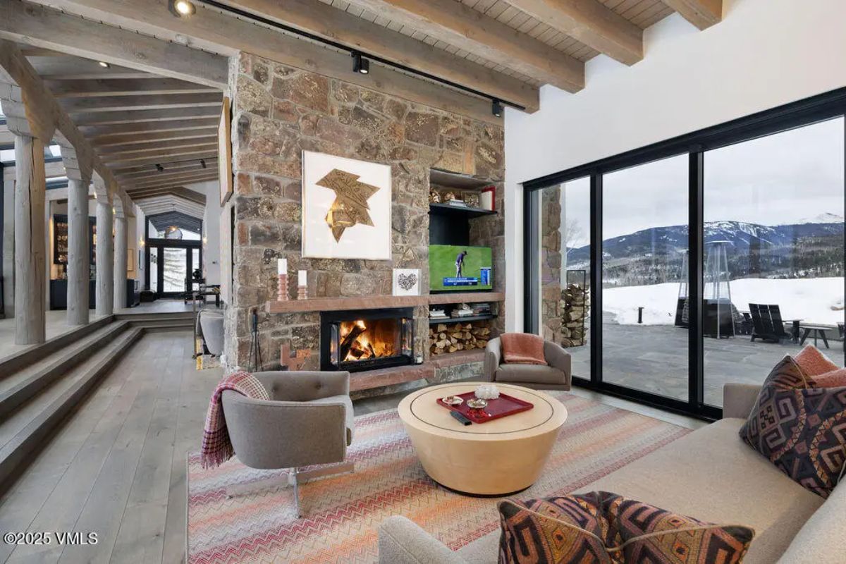 Cozy sitting area with a stone fireplace, built-in shelving, and large sliding glass doors framing mountain views.