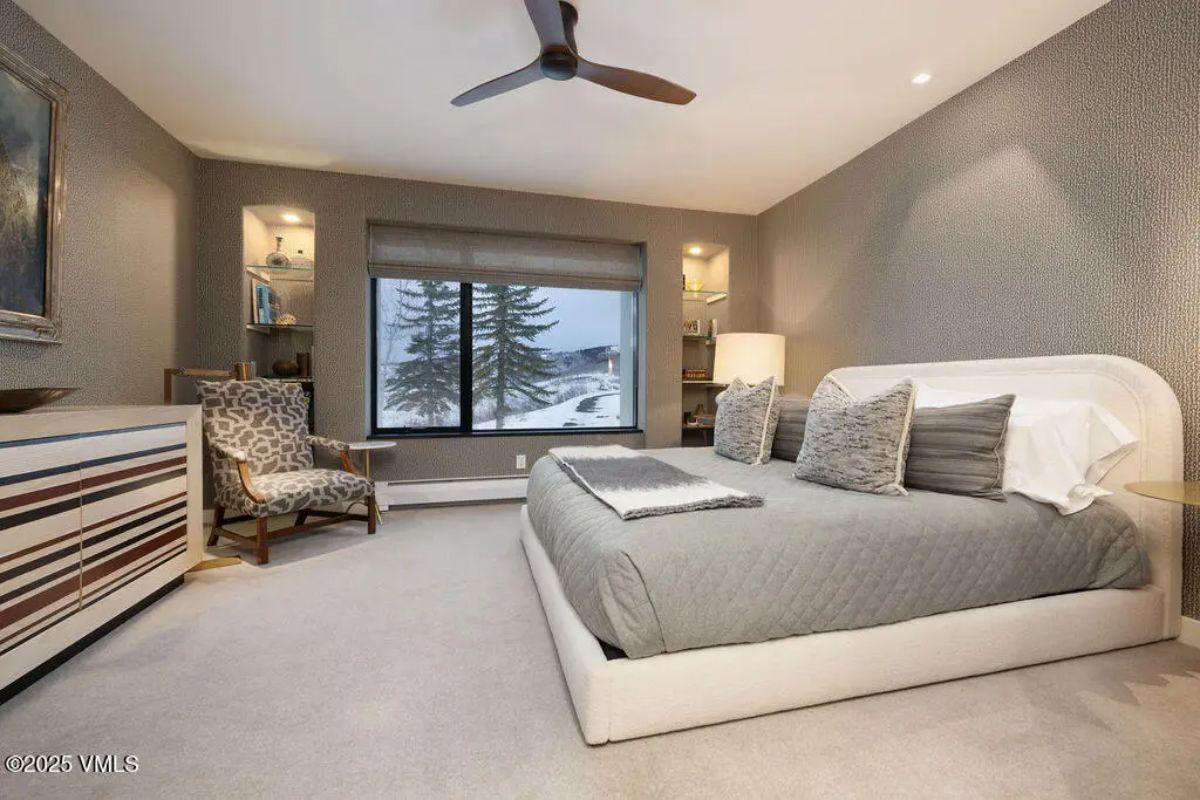 Spacious bedroom with a minimalist design, featuring a large platform bed with neutral bedding and textured accent pillows.