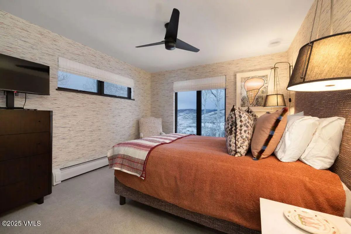 Compact bedroom with a warm, inviting ambiance, highlighted by an earthy orange bedspread and patterned accent pillows.