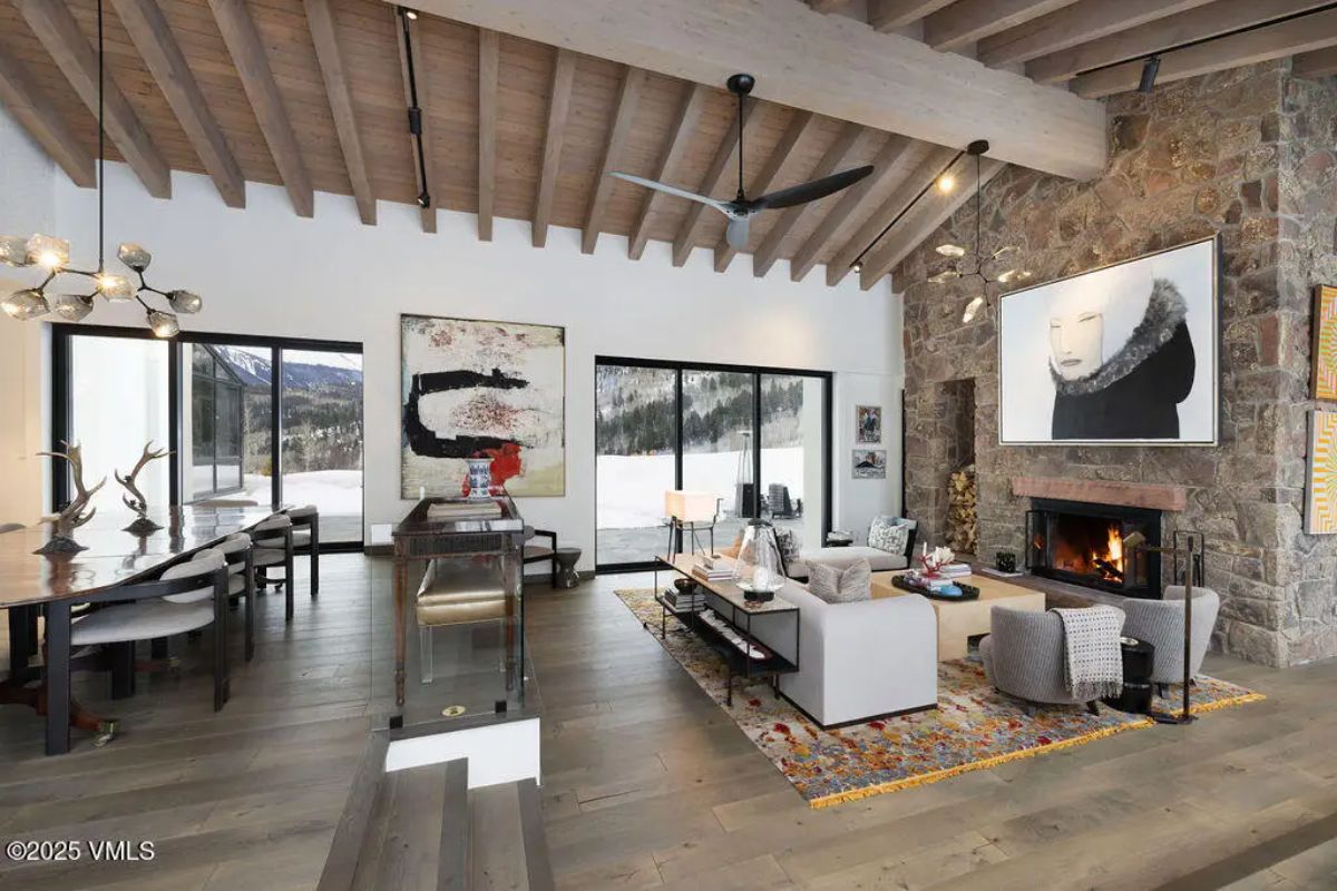 Open-concept living space with vaulted wooden beam ceilings and floor-to-ceiling sliding glass doors.
