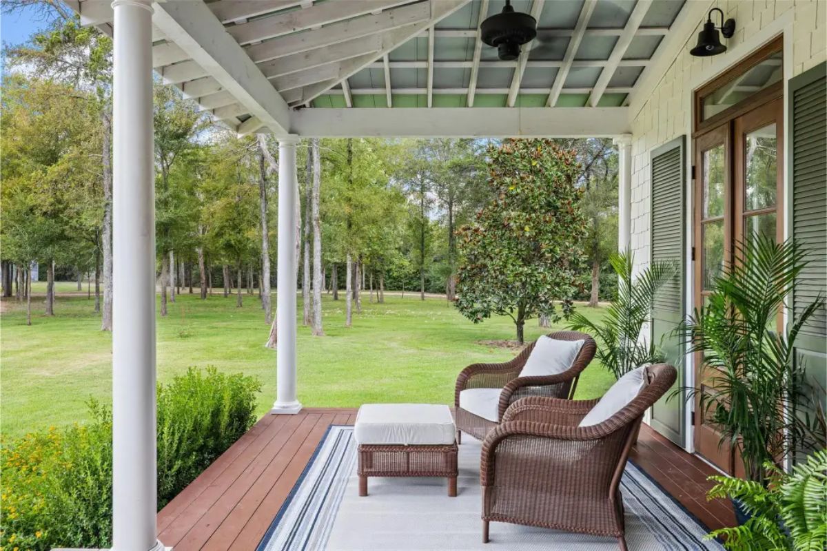 Porch with white columns, wooden flooring, and a slatted ceiling.