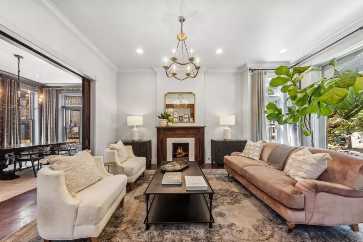 White walls and ceiling contrast with dark furniture and a wooden mantel over the fireplace.