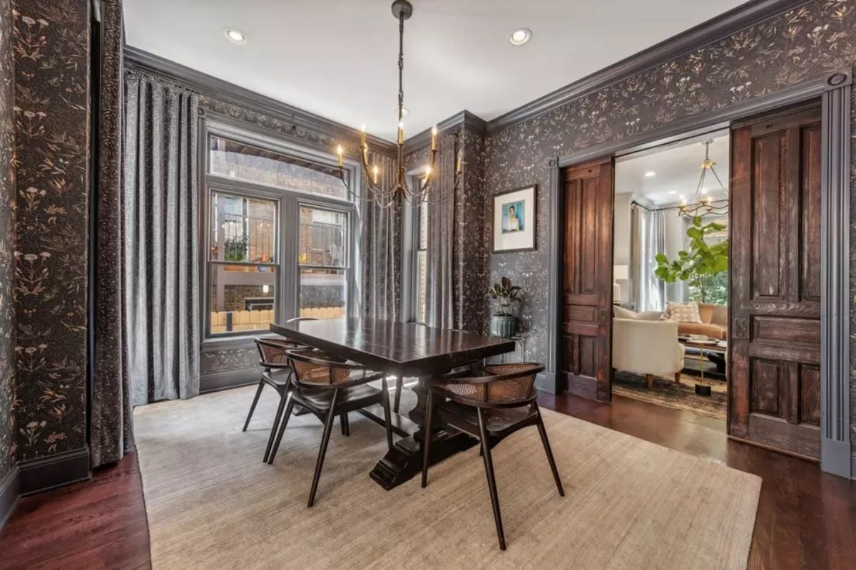 Patterned wallpaper and dark wood trim contrast with a light-colored ceiling and area rug.