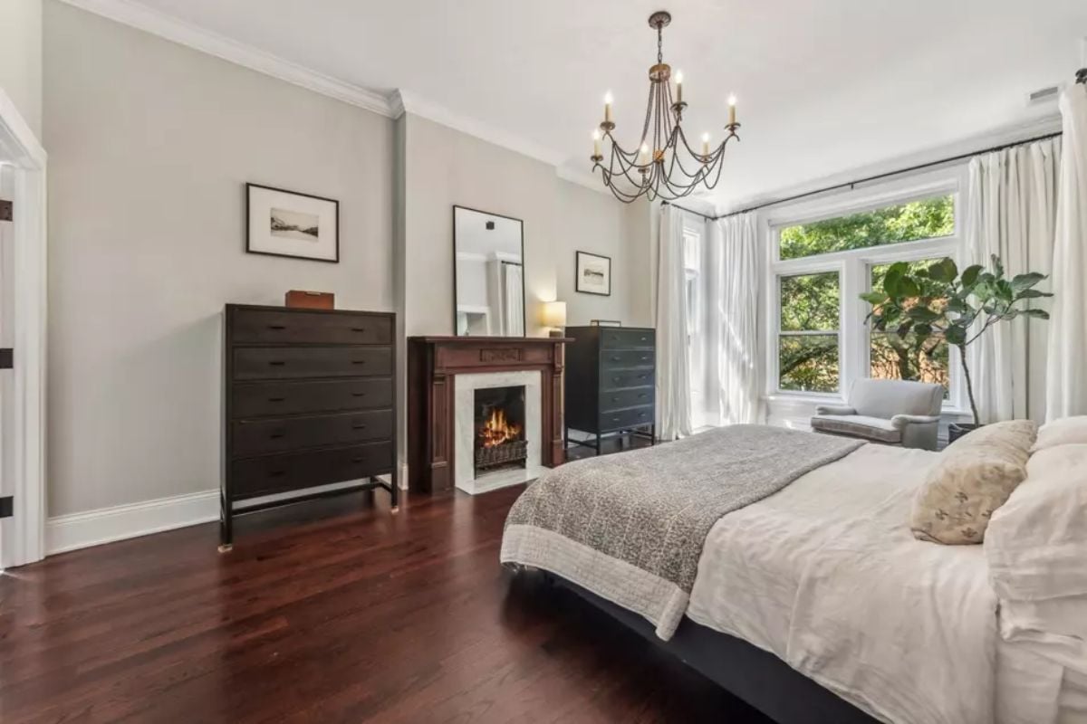 A dark wood fireplace with a marble surround is positioned between two black dressers.