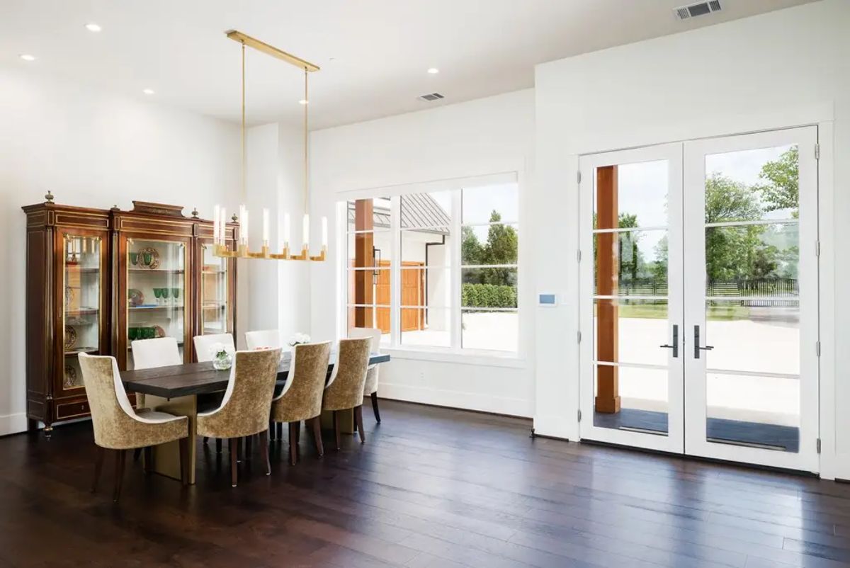 Spacious dining room with a dark wooden table surrounded by upholstered chairs in neutral tones.