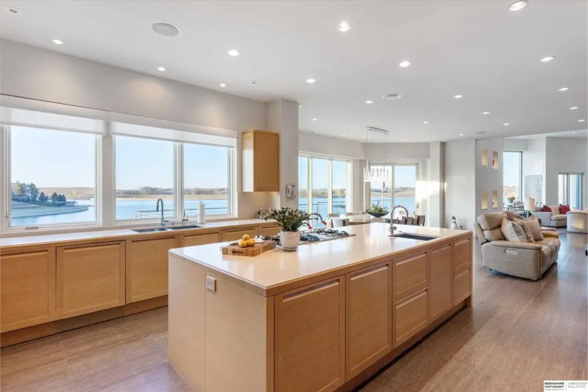 Open-concept kitchen and breakfast nook with minimalist cabinetry, modern lighting, and expansive windows offering panoramic water views. 