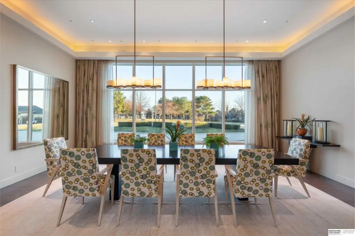 Formal dining room with a long table, upholstered chairs in a playful pattern, and a contemporary lighting fixture, creating an inviting space for gatherings. 