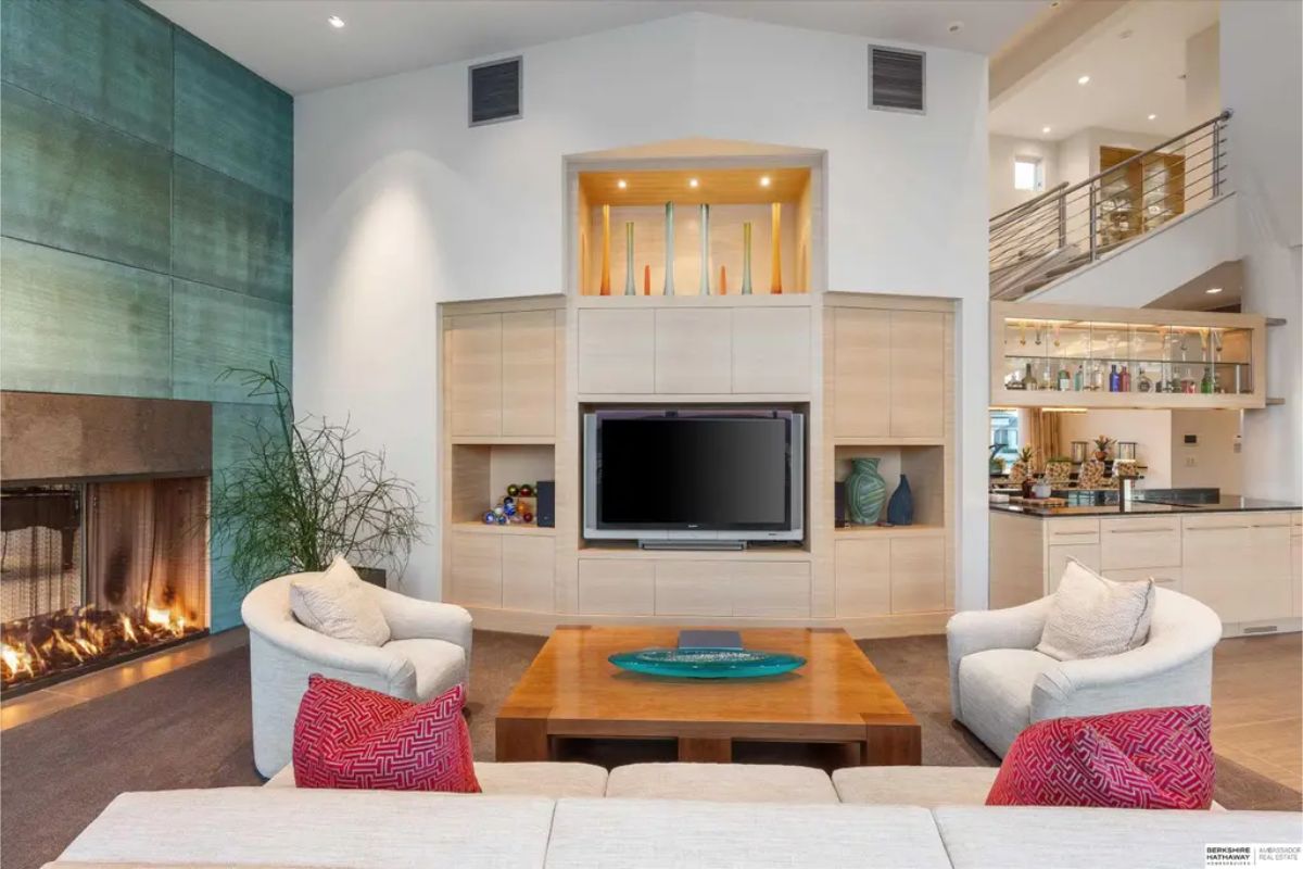 Spacious lounge area with a fireplace, built-in entertainment center, and a wet bar, blending comfort and elegance for a cozy yet luxurious setting. 